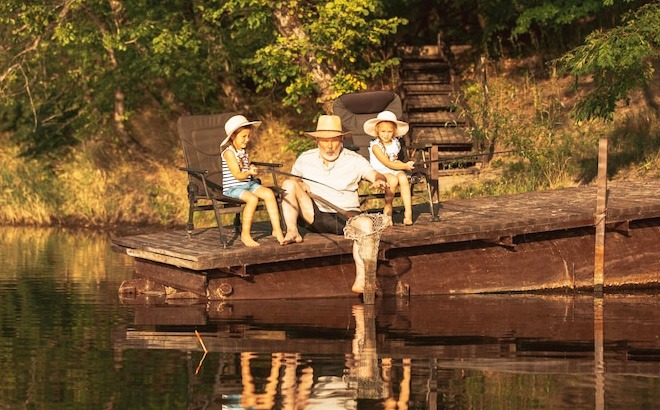 A Person Fishing in a Lake with Two Kids